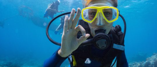 Female scuba diver underwater showing ok signal